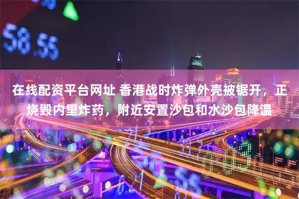 在线配资平台网址 香港战时炸弹外壳被锯开，正烧毁内里炸药，附近安置沙包和水沙包降温